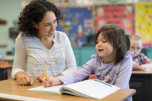 istock First grade girl talking with her teacher in the classroom 1201002532