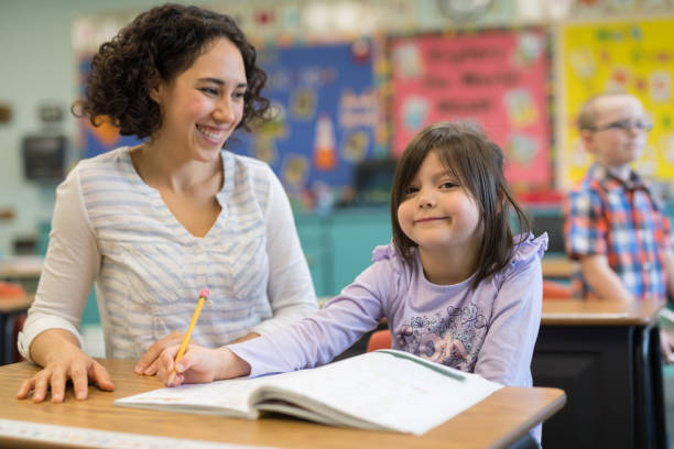 istock First grade girl talking with her teacher in the classroom 1201002534