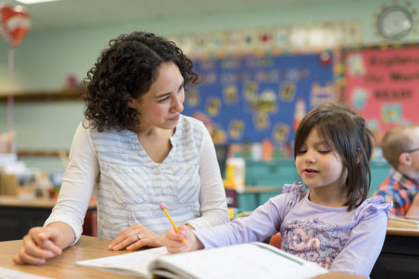 istock Teacher helping a first grade girl in the classroom 1201002536