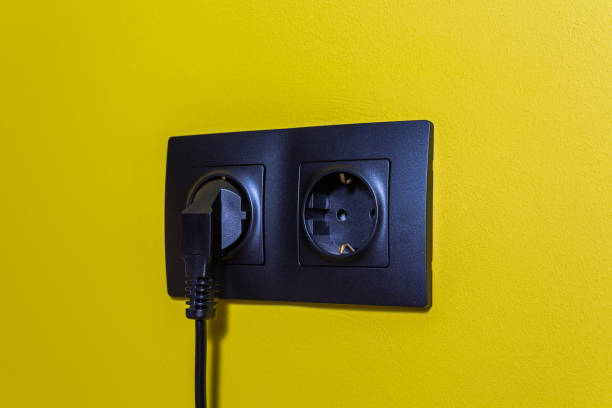 spina nera in presa elettrica in plastica nera. - electric plug outlet human hand electricity foto e immagini stock