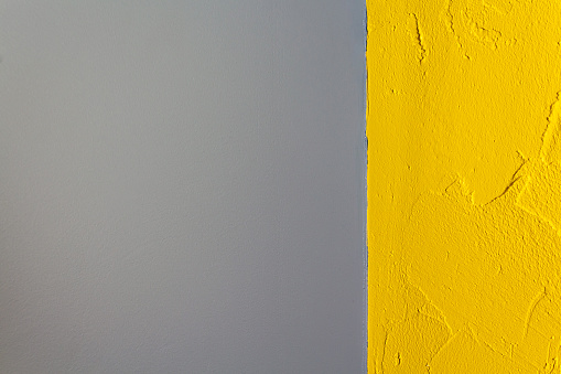 Yellow and grey concrete wall as texture or background. Geometric style. Plastered surface. Poor-quality walls painting.