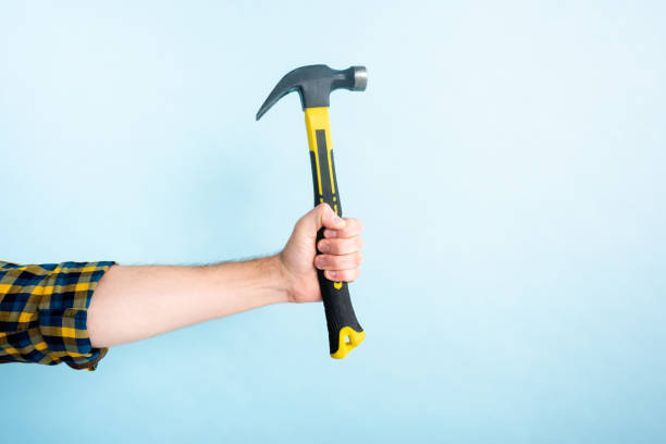 cropped view of workman holding hammer isolated on blue