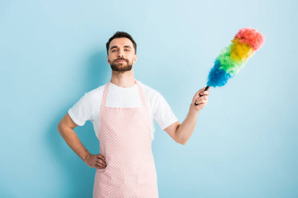 Man cleaning apartment with dusting broom.