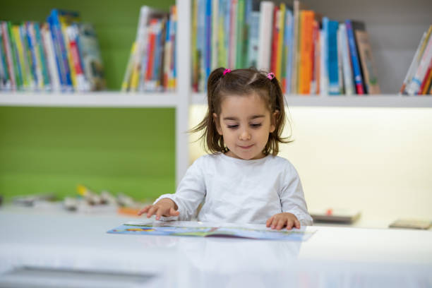 책을 읽고 그것에 대해 생각 웃고 귀여운 어린 소녀 - picture book library preschool bookshelf 뉴스 사진 이미지