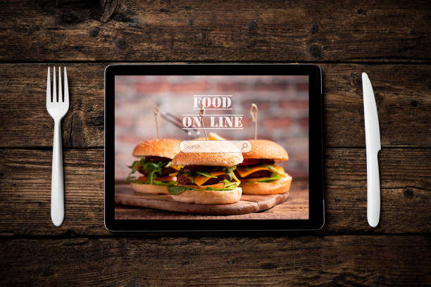 istock An hamburger with lettuce, cheddar cheese, onions, tomato  on wood board displayed on a tablet pc 1201004119