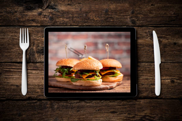 istock An hamburger with lettuce, cheddar cheese, onions, tomato  on wood board displayed on a tablet pc 1201004146