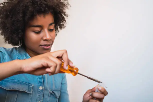 Portrait of young afro woman fixing something with a screwdriver at home. Repair and renovation home concept.
