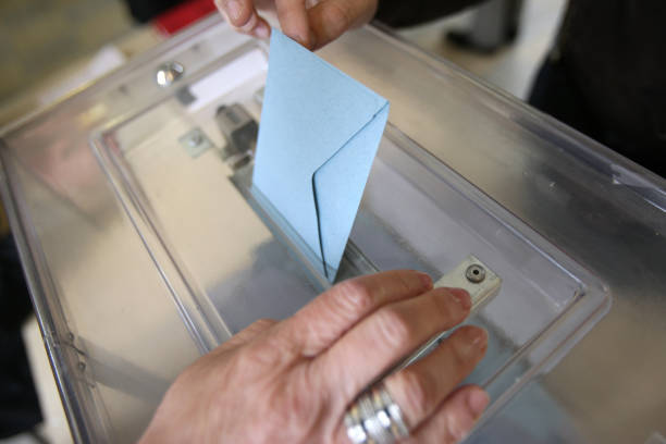 Election envelope and ballot box. Polling station. France. France. 05/06/2012. This colorful image depicts a man placing an election envelope in a plastic ballot box at a polling station. presidential election photos stock pictures, royalty-free photos & images