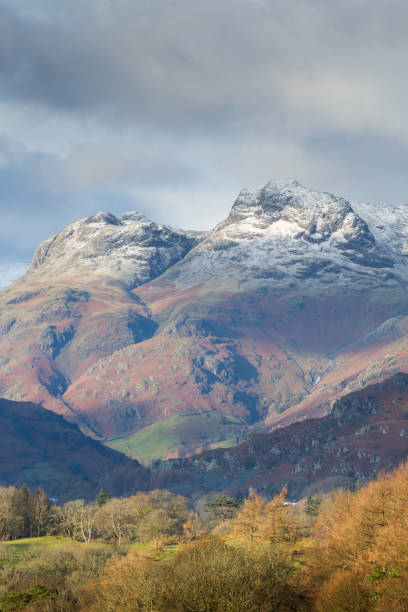 The Langdale Pikes with a dusting of snow, Lake District The Langdale Pikes above Great Langdale in the English Lake District, with a dusting of snow on the mountains and light on the hills and woods in the valley in winter time. langdale pikes stock pictures, royalty-free photos & images