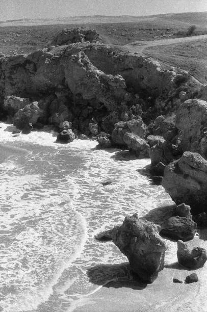 istock Black and white seascape. Empty rocky beach and calm sea grainy image 1201011525