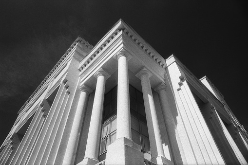 Modern architecture concept. Black and white grainy image of impressive building with columns against black sky copy space