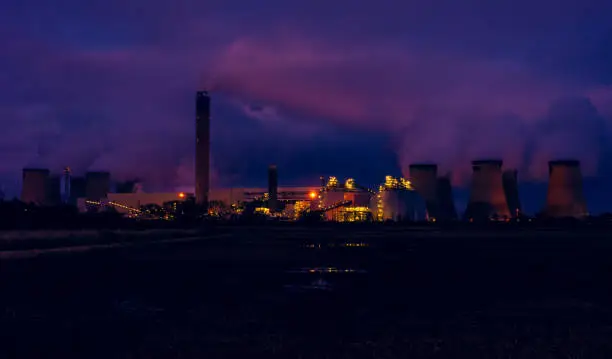 Drax, North Yorkshire, UK.  A cold winter's night in January with the bright lights of a power station reflected in a waterlogged farmer's field.  Horizontal.  Space for copy.