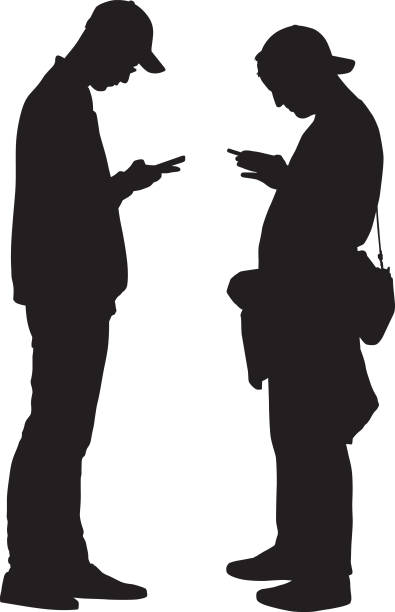 Two Young Men Looking At Smart Phone Vector silhouette of two young men looking at there smart phones. sideways baseball hat stock illustrations