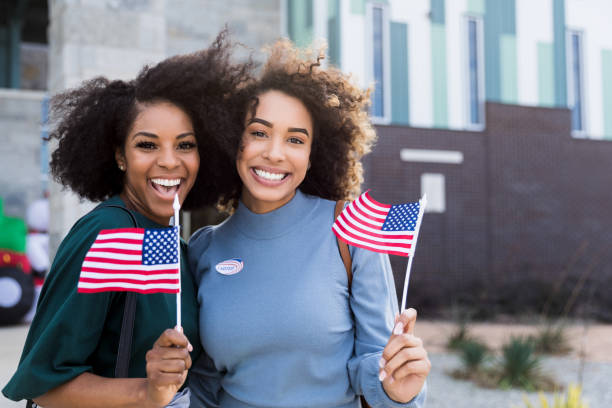 istock Two female friends wave flags and smile after voting 1201018716
