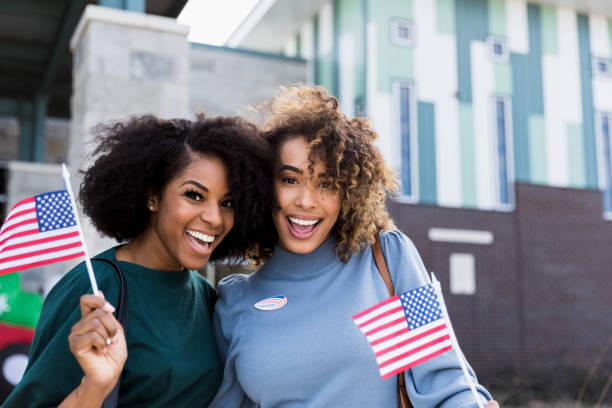 istock Two friends waving flags after voting smile for camera. 1201018726