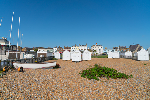 Deal England - August 19 2019; Typical British coastal town with boat pulled up on stony beach, beach sheds behind and street of traditional buildings.