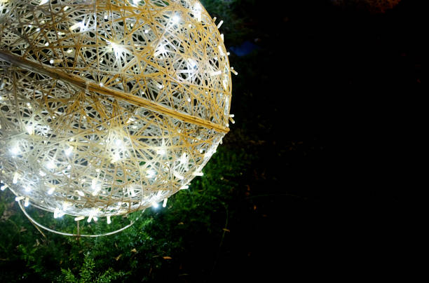 Part of a globe shaped ornament, lit with sparkly fairy lights, against black night sky.
