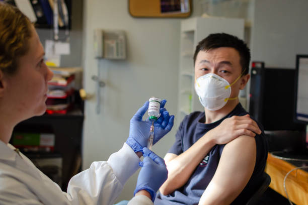 mâle chinois recevant le vaccin de coronavirus dans la clinique - fondation de recherche photos et images de collection