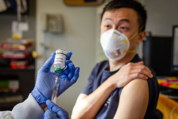 Chinese male receiving coronavirus vaccine in clinic Illustrative picture of Chinese male getting vaccinated against coronavirus syringe photos stock pictures, royalty-free photos & images