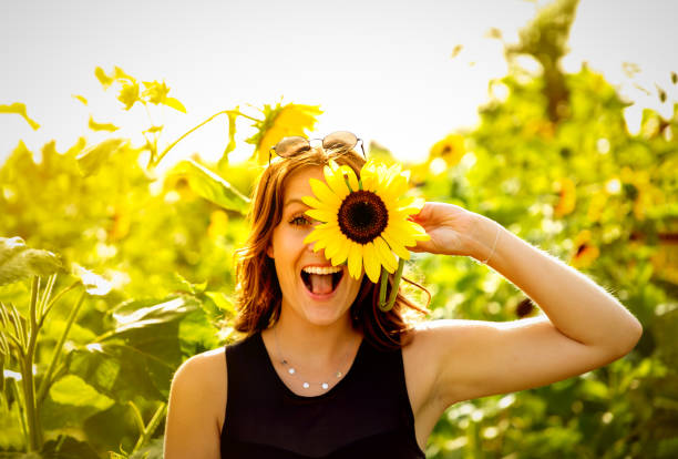 Young woman laughs with a sunflower on her face