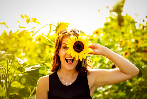 Young woman laughs with a sunflower on her face.