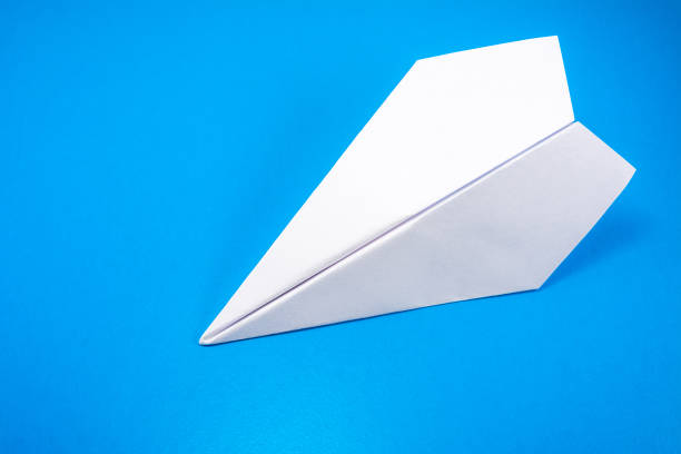 istock paper airplane made of white paper on a light blue background, copy space 1201027232