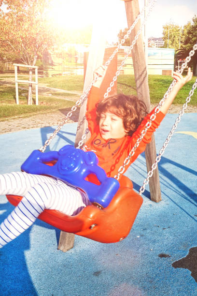 istock Happy laughing little boy in swing on playground 1201028072