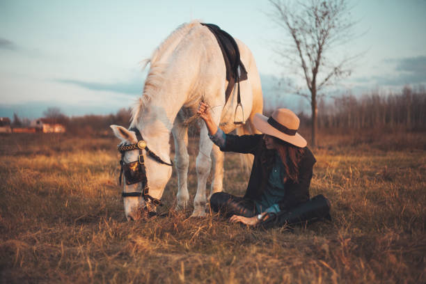istock Young woman posing next to her white horse 1201028075