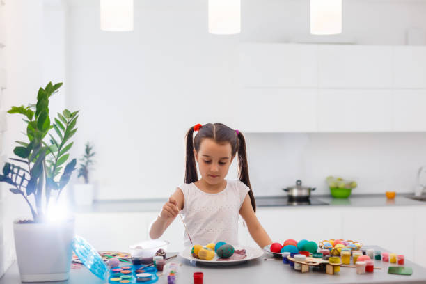 istock Little girl painting Easter eggs in the kitchen 1201029401