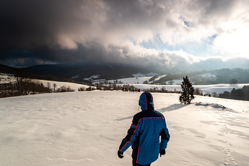 Active Man Walking in Deep Snow in Mountains at Sunrise in Winter Time.
