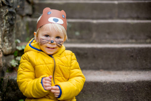 istock Adorable blond toddler child with bear mask and painted face 1201032018
