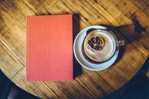 Book and a cup of latte on wooden table in coffee shop