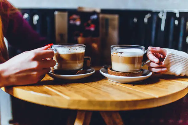 Hands of female friends with coffee cups