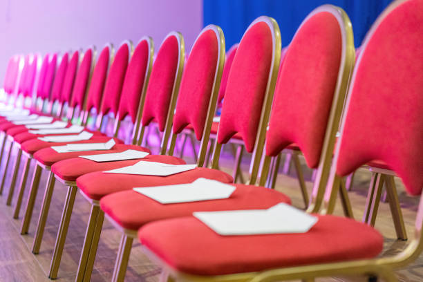 Rows of red chairs in conference hall, empty meeting or event room. Empty guest seats.