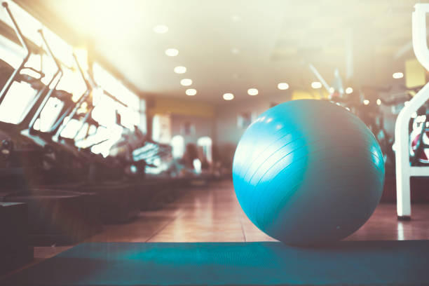 Beautiful girl doing a balancing drill on a fit ball at home, arms stretched in front of her.