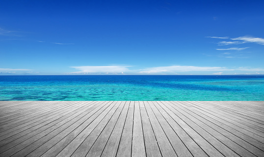 Wooden walkway beside tropical ocean with clear sky background