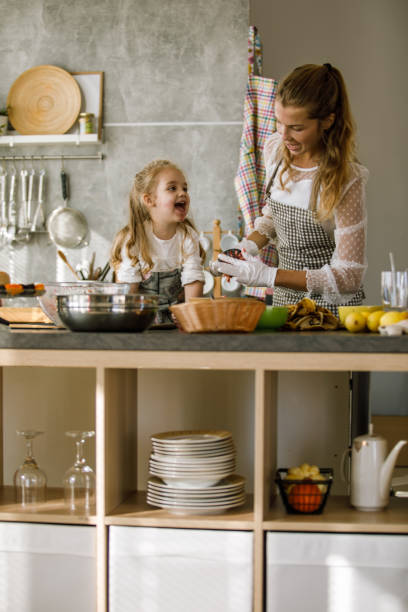 istock Cheerful three year old having fun while making a banana snack with her mother 1201050212