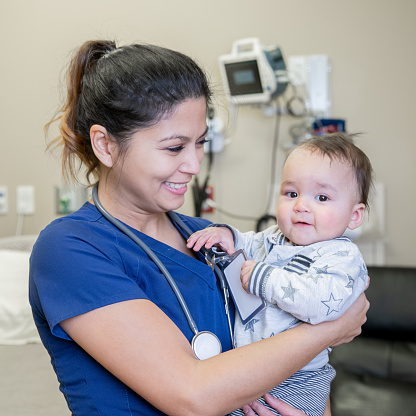 Nurse smiles while holding young patient