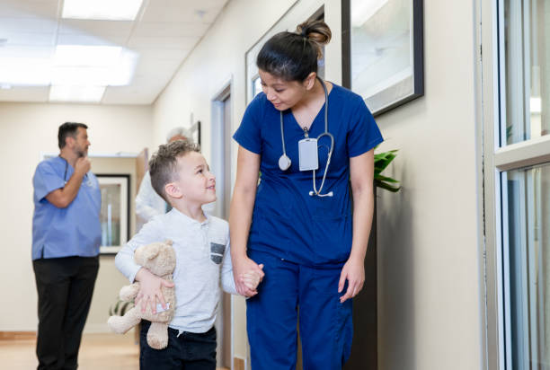 istock Nurse holding young boys hand while walking down hospital hallway 1201050286