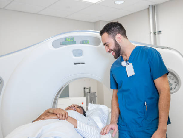 istock Male technician checking on patient before they enter CT scan machine 1201050307