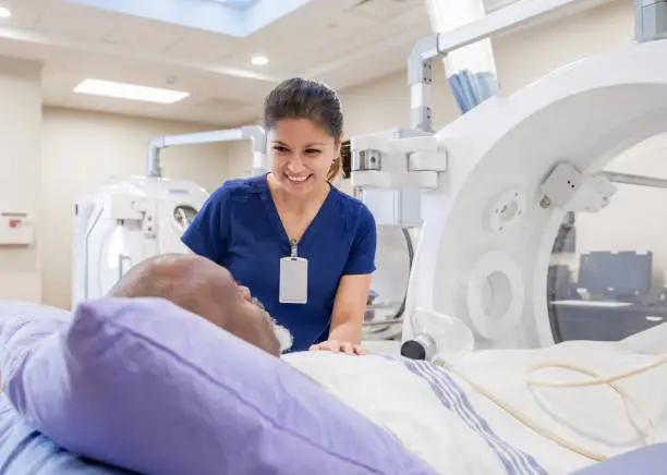 Photo of Female nurse prepares senior male for treatment in hyperbaric chamber