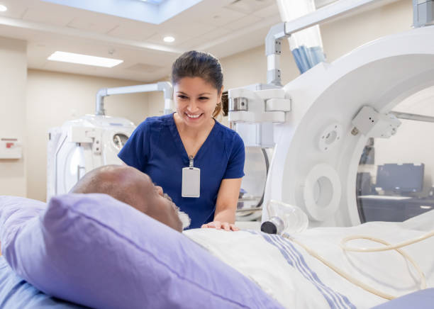 female nurse prepares senior male for treatment in hyperbaric chamber - radiologist imagens e fotografias de stock