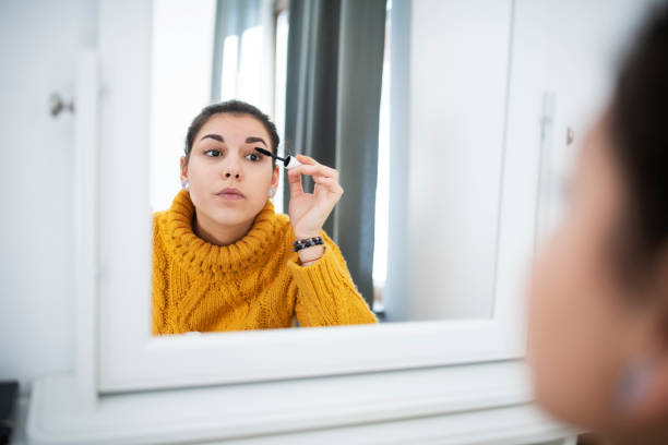 donna che applica il mascara allo specchio - living room elegance women long hair foto e immagini stock