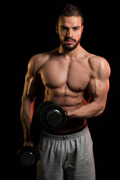 istock Model Exercising Biceps With Dumbbells On Black Background 1201050381