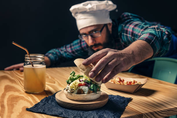 istock chef finishing up his vegan burger on a wood table 1201050475