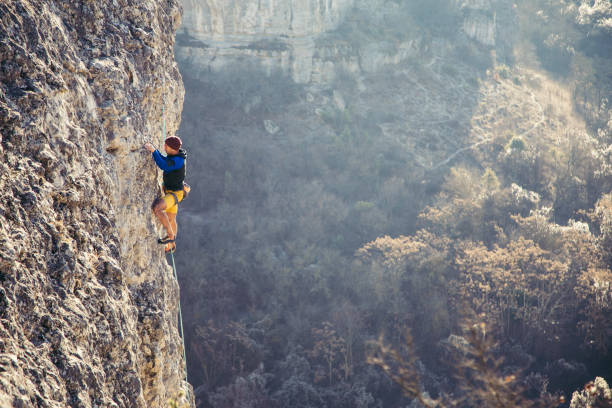 l'homme grimpe un rocher. - climbing clambering mountain rock climbing photos et images de collection