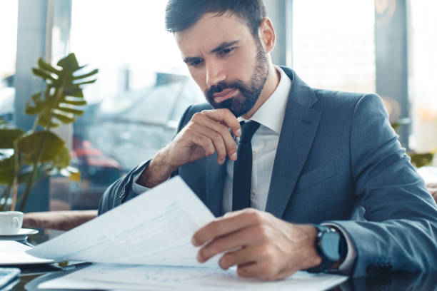 istock Businessman sitting in a business center restaurant reading documents concerned 1201051210