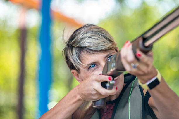 retrato de mujer adulta enfocada apuntando con pistola en el campo de tiro - foto de archivo - shooting women gun shotgun fotografías e imágenes de stock