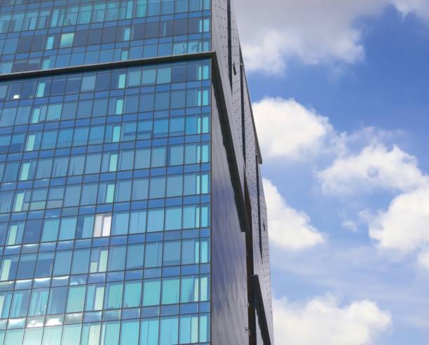 istock Modern office building exterior. Blue glass facade and blue sky with sparse clouds. 1201056119