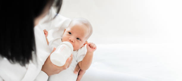 Mother feeding asian baby with bottle of milk, banner copy space Mother feeding asian baby with bottle of milk, banner copy space babyhood photos stock pictures, royalty-free photos & images